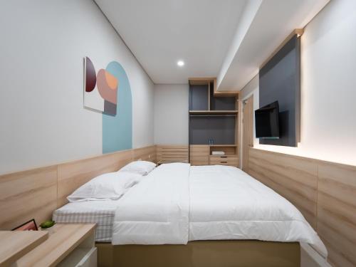 a bedroom with a white bed and a television at Cove Bona Sort Pasar Baru in Jakarta