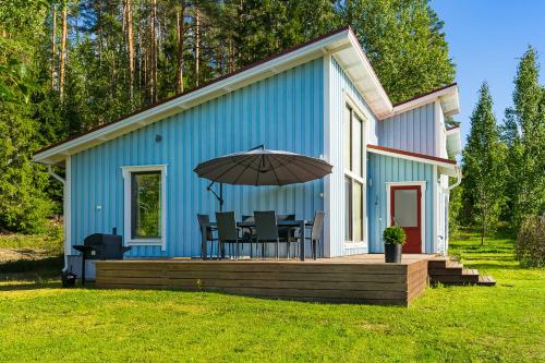 a blue house with a table and an umbrella on a deck at Tammikallio in Tjuda