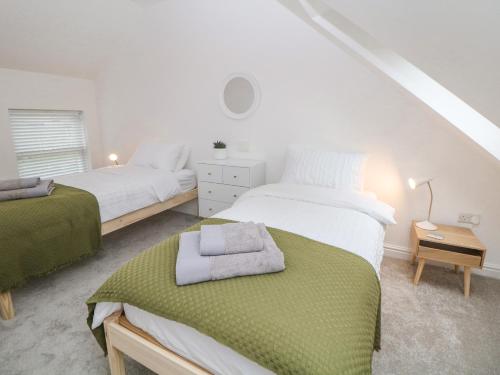 Un dormitorio con 2 camas y una mesa con una toalla. en Potters Cottage en Sheffield