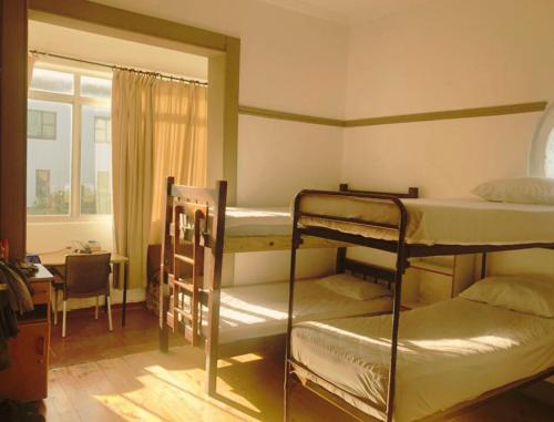 1 dormitorio con 2 literas, escritorio y ventana en Ben Your Friend Youth Foundation, en Ciudad del Cabo