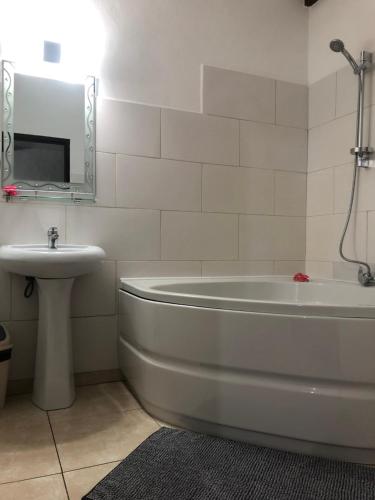 ein weißes Badezimmer mit einer Badewanne und einem Waschbecken in der Unterkunft HCS Bungalows Turtle Bay Rustic Bungalow in Au Cap