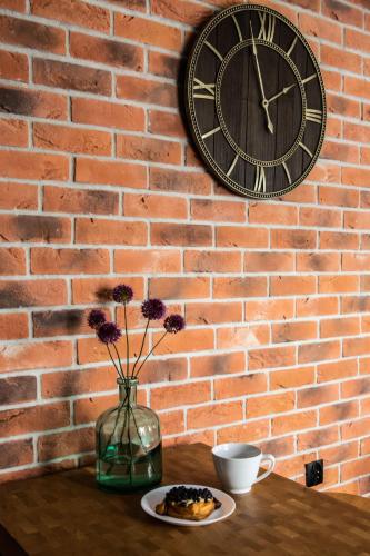 a brick wall with a clock and a table with a plate of food at Apartament Ducha N°9 in Toruń