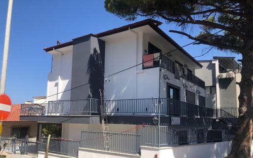 a white building with a balcony and a tree at Lulubay Rooms & Suites in Kusadası