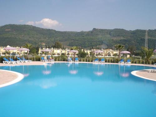 een groot zwembad met stoelen en gebouwen op de achtergrond bij Stunning Studio holiday apartment for 23 on resort, close to beach with 2 pools in Pizzo