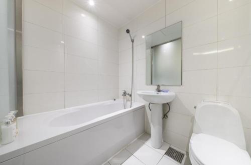Hotel Lien في بوسان: حمام أبيض مع حوض ومرحاض وحوض استحمام