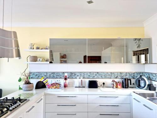 a white kitchen with a sink and a stove at Peaceful penthouse with views 3 min walk to the beach in Marsaskala
