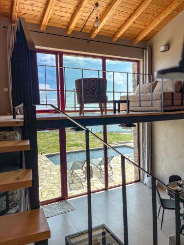 a loft bed in a room with a large window at Modern Stone Villas with Swimming Pool in Aliveri
