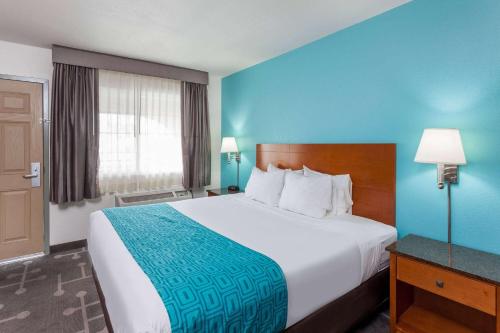 a hotel room with a large bed with a blue wall at Howard Johnson by Wyndham National City/San Diego South in National City