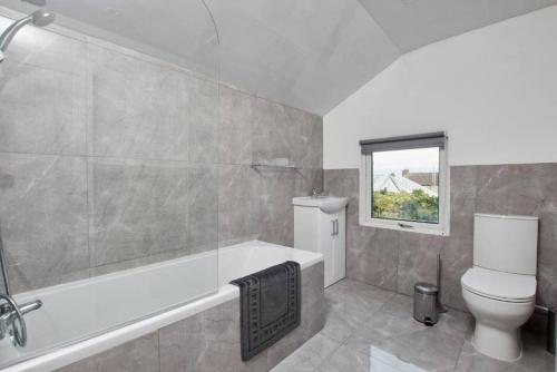 ein Badezimmer mit einer Badewanne, einem WC und einem Waschbecken in der Unterkunft The Stunning Central Rugby Gem - Sleeps 10 in Rugby