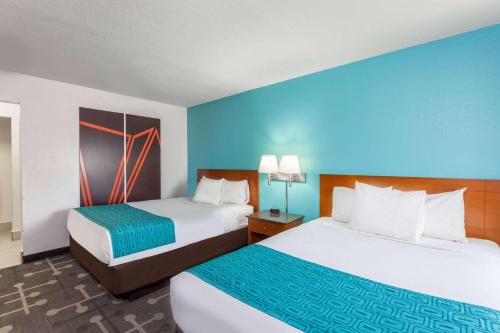 duas camas num quarto de hotel com paredes azuis em Howard Johnson by Wyndham National City/San Diego South em National City