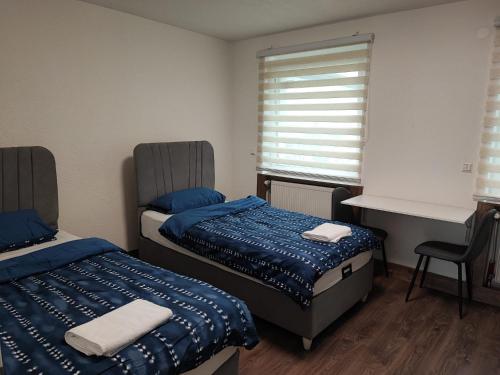 1 Schlafzimmer mit 2 Betten, einem Schreibtisch und einem Fenster in der Unterkunft Heidenheimer Zimmer in Heidenheim