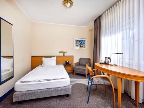 a hotel room with a bed and a desk at Mercure Hotel Düsseldorf City Center in Düsseldorf