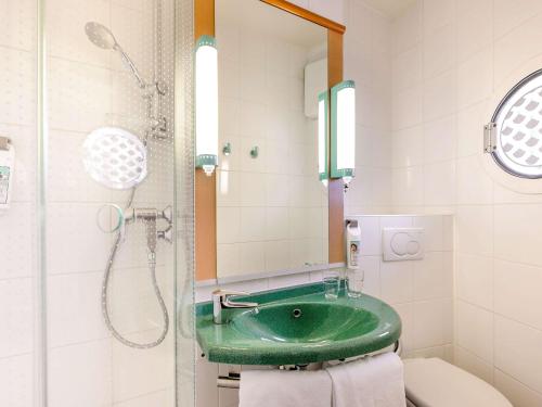 a bathroom with a green sink and a shower at ibis Essen Hauptbahnhof in Essen