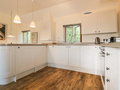 a kitchen with white cabinets and a hardwood floor at Pirata in St Austell