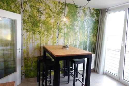 ein Esszimmer mit einem Tisch und einem Wandbild von Bäumen in der Unterkunft Stilvolles Design Apartment mit Rheinblick inkl Netflix & Parkplatz in Düsseldorf