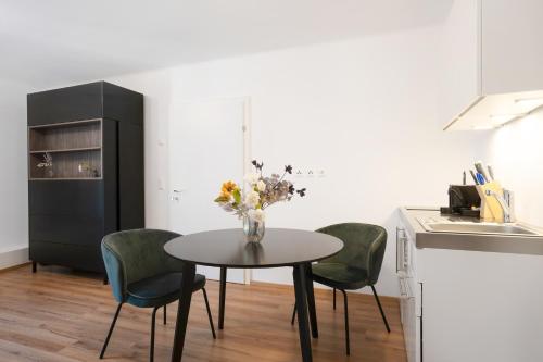 a dining room table with green chairs and a kitchen at easy flat Villach main plaza in Villach