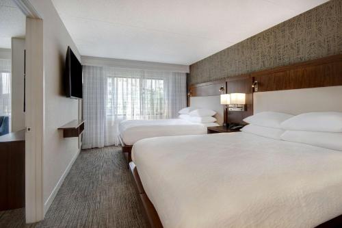 a hotel room with two beds and a television at Embassy Suites by Hilton Detroit Metro Airport in Romulus