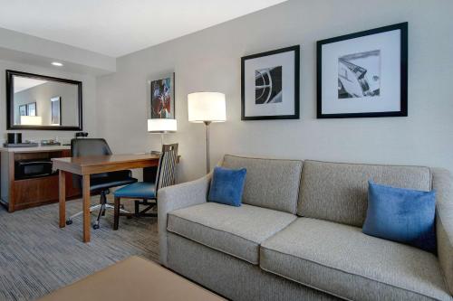 a living room with a couch and a desk at Embassy Suites by Hilton Detroit Metro Airport in Romulus