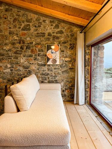 a couch sitting in a room with a brick wall at Modern Stone Villas with Swimming Pool in Aliveri