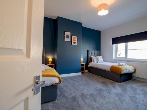 1 dormitorio con 2 camas y pared azul en Pass the Keys Stylish Terrace with Free Parking, en Blythe