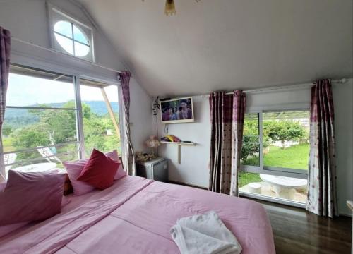 a bedroom with a pink bed and a large window at เขาค้อออฟเลิฟ in Khao Kho