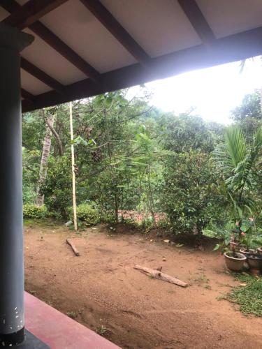 uma vista para um campo de terra com árvores e arbustos em BuildZone Home Stay em Balangoda