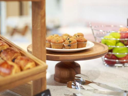 a table with a plate of muffins and a plate of fruit at Adagio Antwerp City Center in Antwerp