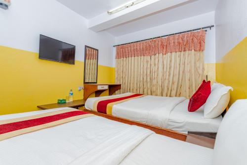 a hotel room with two beds and a flat screen tv at OYO 807 Hotel Grand Tokyo in Kathmandu