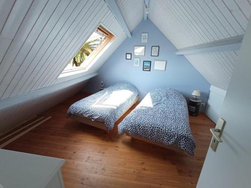 Cette chambre mansardée comprend un lit et une fenêtre. dans l'établissement Brennick, Maison 4 pers proche mer et plage, à Clohars-Carnoët