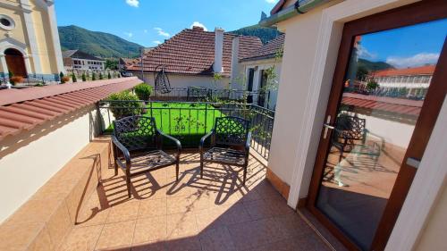 a balcony with two chairs and a green door at Conacul Poetilor in Gura Rîului