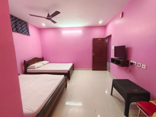 a room with two beds and a pink wall at Le Paradise Inn in Puducherry