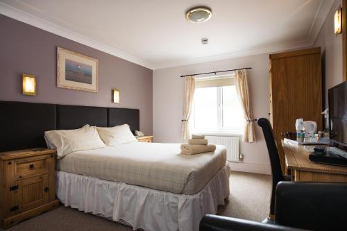a bedroom with a bed and a desk with a computer at The Coach House Hotel in Pembroke