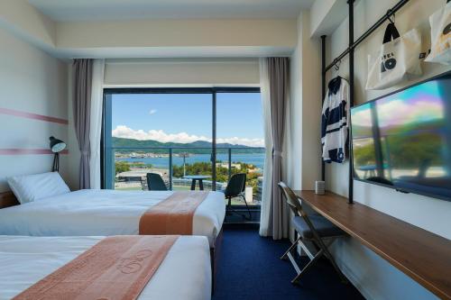 玉野市にあるKEIRIN HOTEL 10 by 温故知新のベッド2台と大きな窓が備わるホテルルームです。