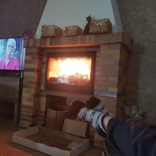 a person sitting in front of a fireplace with a tv at Casa Rural La Costa in La Lapa