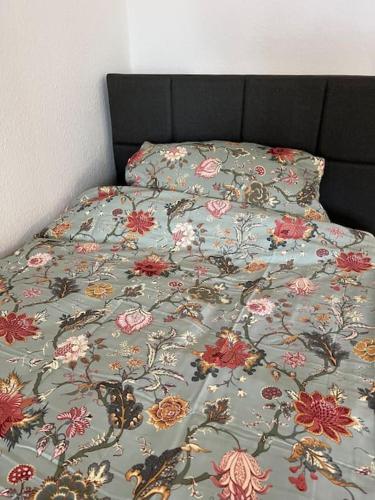 a bed with a floral comforter on it at City Appartement direkt am Schloss! in Karlsruhe