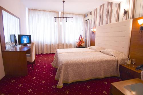 a hotel room with a bed and a desk and a television at Arena Tarnovo Hotel -Free Large Private Parking in Veliko Tŭrnovo