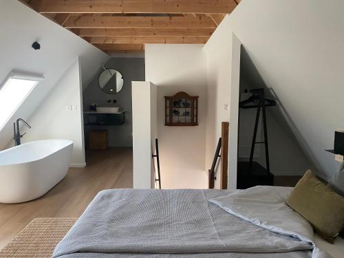 a bedroom with a tub and a bed and a sink at B&B Het Zwarte Schaap in Albergen