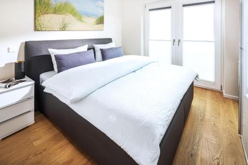 1 dormitorio con 1 cama grande con almohadas blancas y moradas en Villa Sohn Deck7, en Juist