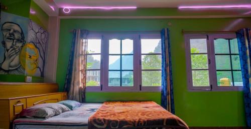a bedroom with green walls and a bed and windows at Destination of peace kasol in Kasol