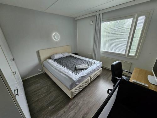 1 dormitorio con cama, escritorio y ventana en Tilava kaksio, saunalla ja sähköauton latauksella., en Tampere