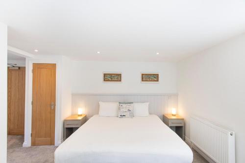 a bedroom with a large white bed and two lights at Tregenna Castle Resort in St Ives