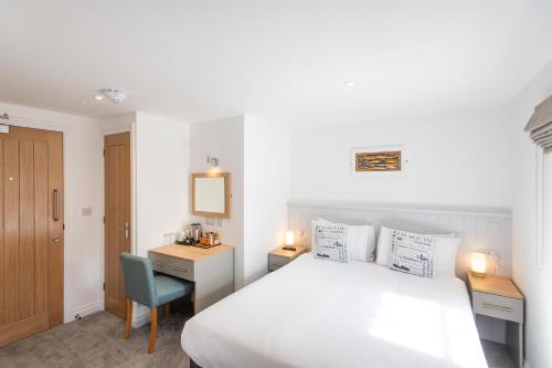 a bedroom with a white bed and a desk and a chair at Tregenna Castle Resort in St Ives