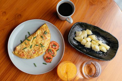 a table with a plate of breakfast food and a cup of coffee at HIMA Bungalows in Lagudri