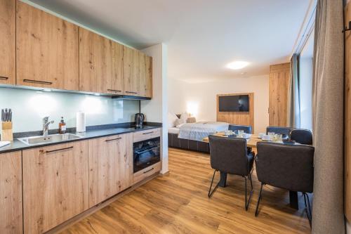 Appartements by Hofer في كابرون: مطبخ وغرفة طعام مع طاولة وسرير