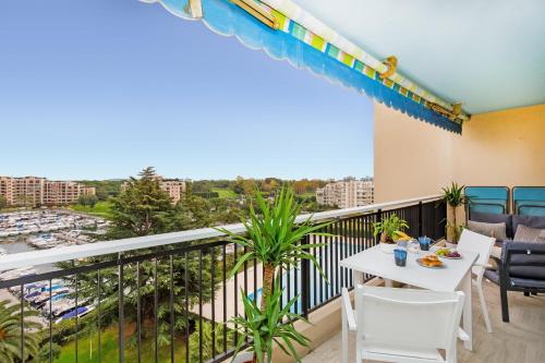 a balcony with a table and chairs and a view of a harbor at Appartement à 2 pas du golf in Mandelieu-la-Napoule
