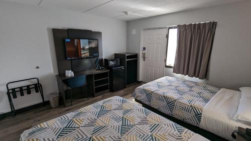 a bedroom with two beds and a desk and a television at Motel 6-Leominster, MA in Leominster