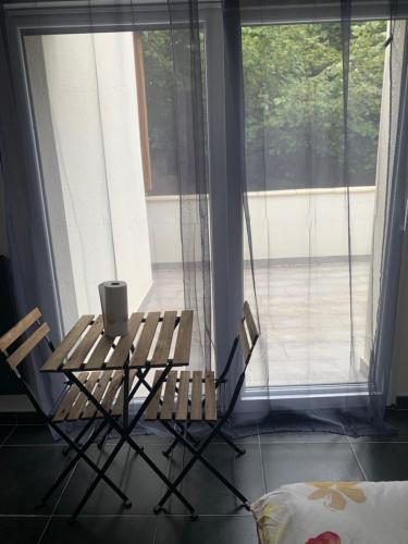 une table et deux chaises devant une fenêtre dans l'établissement Jolie maisonnette avec terrasse Nancy centre, à Nancy