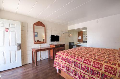1 dormitorio con cama, escritorio y espejo en Centralia Motel near Downtown by OYO, en Centralia