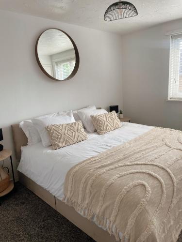 a white bedroom with a large bed with a mirror at Cosy & stylish home from home in Peterborough