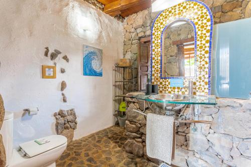 a bathroom with a stone wall with a sink and a toilet at Eco Village Finca De Arrieta in Tabayesco
